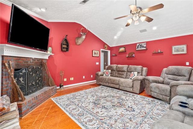 living room with wood-type flooring, lofted ceiling, ornamental molding, and a fireplace