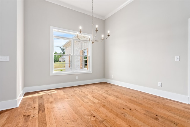 unfurnished dining area with ornamental molding, light wood-type flooring, a notable chandelier, and baseboards