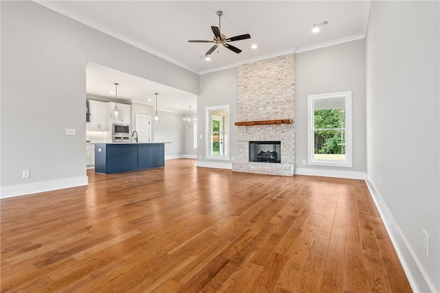 unfurnished living room featuring ornamental molding, a sink, plenty of natural light, and light wood finished floors