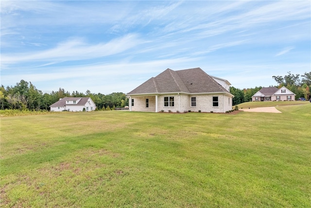 rear view of property featuring a shingled roof and a yard