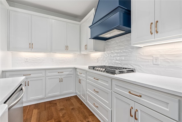 kitchen featuring stainless steel appliances, dark wood-type flooring, white cabinets, custom exhaust hood, and decorative backsplash