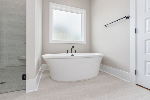 bathroom with a freestanding tub, baseboards, and a stall shower