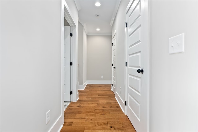 corridor with baseboards, light wood finished floors, ornamental molding, and recessed lighting