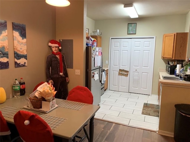 dining room featuring light wood-type flooring, electric panel, and sink