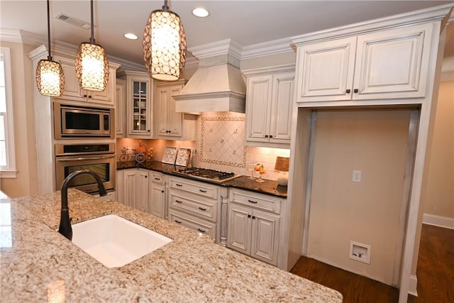 kitchen with dark stone counters, glass insert cabinets, decorative light fixtures, stainless steel appliances, and a sink