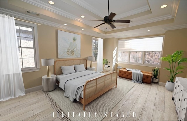 bedroom with light wood finished floors, a raised ceiling, baseboards, ornamental molding, and visible vents