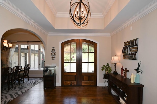 entrance foyer featuring a raised ceiling, french doors, dark wood-type flooring, and a notable chandelier