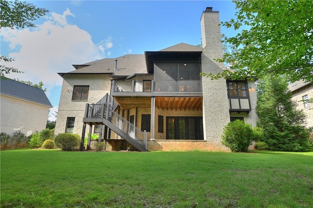 rear view of property featuring a chimney, stairs, a wooden deck, a lawn, and a sunroom