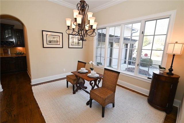 dining area with baseboards, ornamental molding, dark wood finished floors, and arched walkways