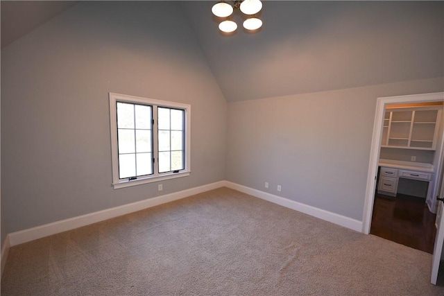 spare room with lofted ceiling, dark colored carpet, and baseboards