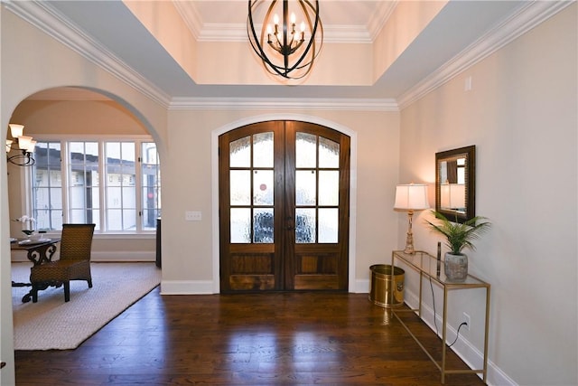 entrance foyer featuring a tray ceiling, french doors, arched walkways, dark wood finished floors, and a chandelier