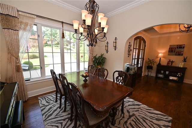 dining area with dark hardwood / wood-style flooring, crown molding, and an inviting chandelier