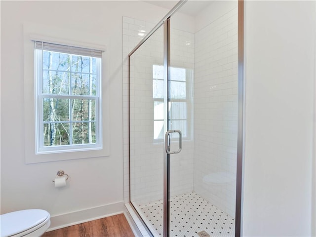 bathroom featuring hardwood / wood-style flooring, toilet, a healthy amount of sunlight, and walk in shower