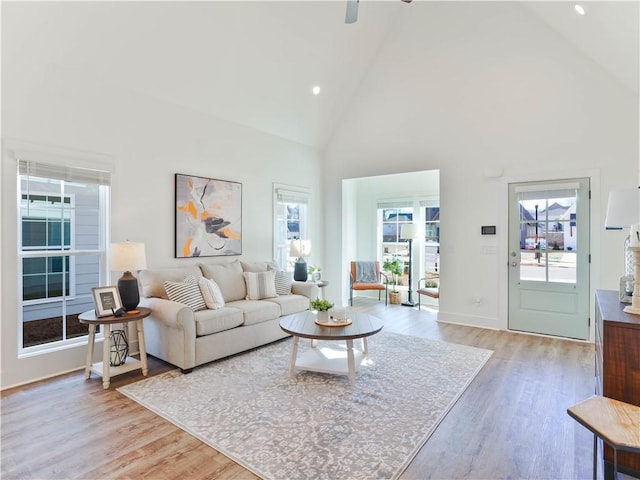 living room with plenty of natural light, high vaulted ceiling, and light wood-type flooring