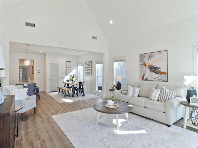 living room with high vaulted ceiling and light hardwood / wood-style floors