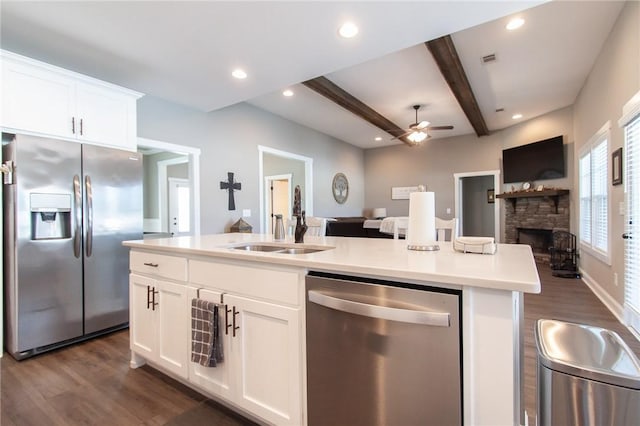 kitchen featuring stainless steel appliances, open floor plan, a sink, and beam ceiling