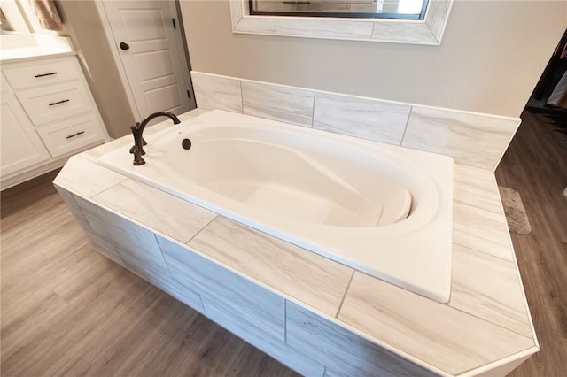 bathroom with a garden tub and wood finished floors