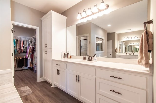 bathroom with a stall shower, wood finished floors, vanity, and a walk in closet