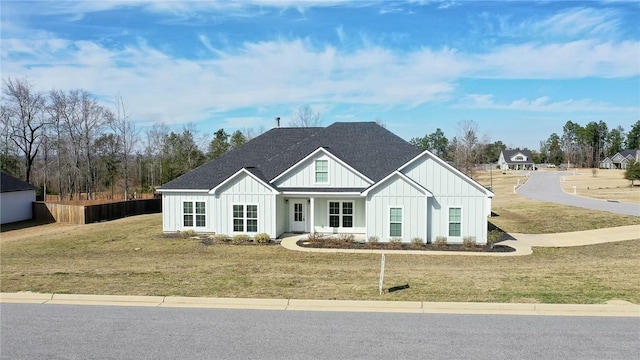 modern farmhouse featuring board and batten siding, a front yard, and roof with shingles