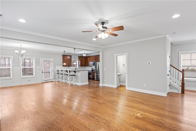 unfurnished living room featuring ornamental molding, ceiling fan with notable chandelier, and light hardwood / wood-style flooring