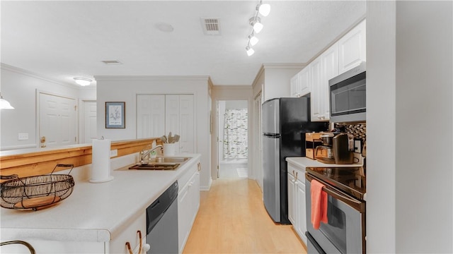 kitchen with white cabinets, appliances with stainless steel finishes, ornamental molding, and sink