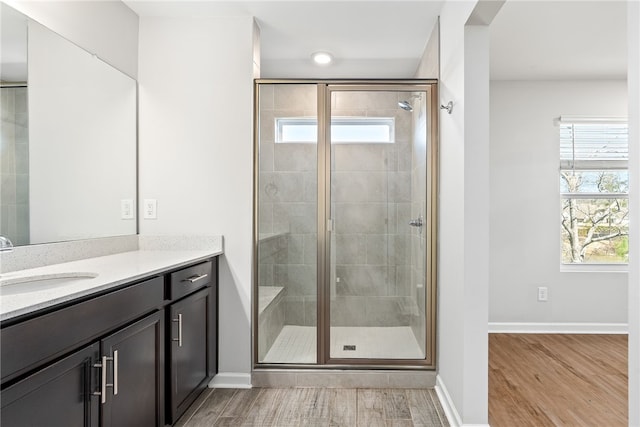 full bathroom featuring vanity, wood finished floors, baseboards, and a stall shower