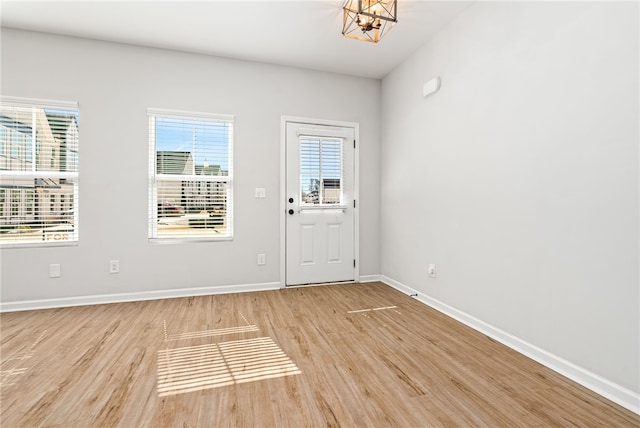 entryway with light wood-type flooring, baseboards, plenty of natural light, and a chandelier