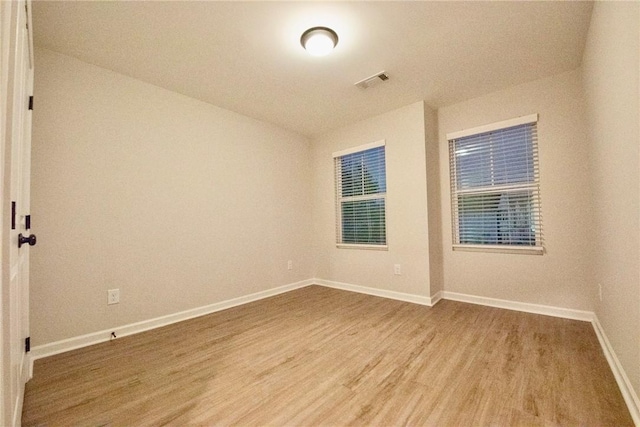 spare room featuring visible vents, baseboards, and wood finished floors