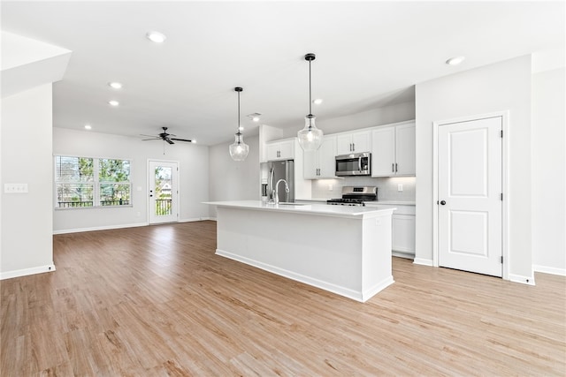 kitchen featuring light wood finished floors, backsplash, appliances with stainless steel finishes, and light countertops