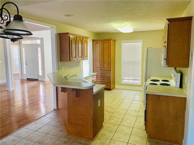 3672 Hawthorne Ct, Auburn, AL 36830 - kitchen with white appliances, a peninsula, light countertops, a kitchen breakfast bar, and light tile patterned floors