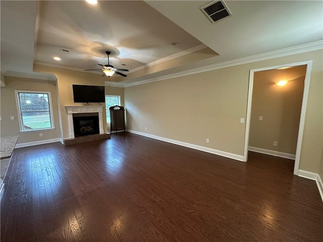 unfurnished living room featuring a raised ceiling, a tile fireplace, ceiling fan, and crown molding