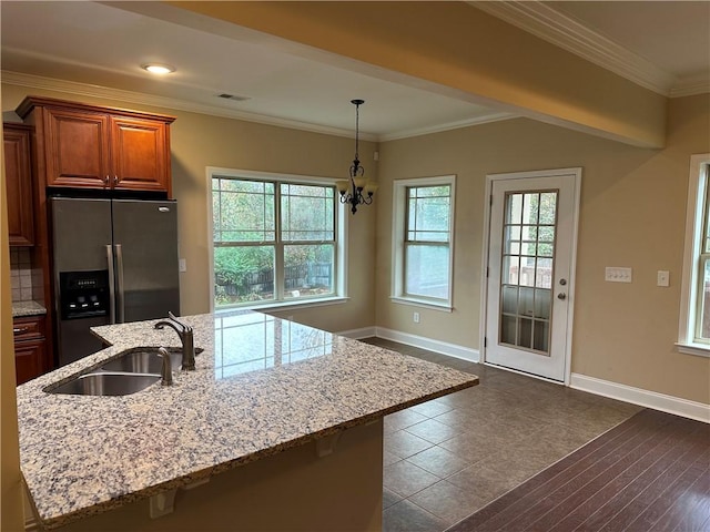 kitchen featuring an inviting chandelier, a center island with sink, crown molding, sink, and stainless steel fridge with ice dispenser