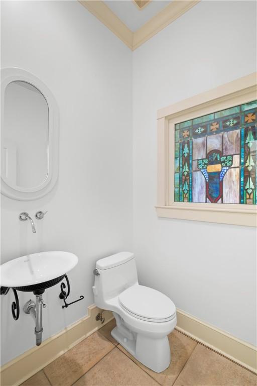 bathroom featuring tile patterned flooring, toilet, and ornamental molding