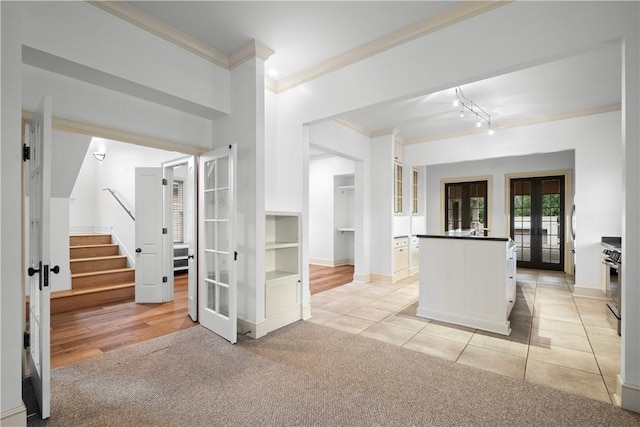 kitchen with white cabinets, french doors, light colored carpet, and crown molding