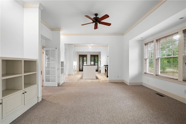 unfurnished living room featuring french doors, light colored carpet, ceiling fan, and crown molding