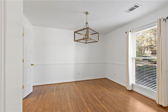 empty room featuring a chandelier and wood-type flooring