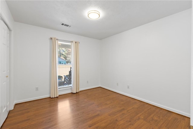 unfurnished room with wood-type flooring and a textured ceiling