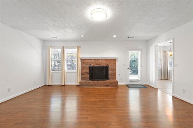 unfurnished living room featuring a fireplace, wood-type flooring, and a textured ceiling