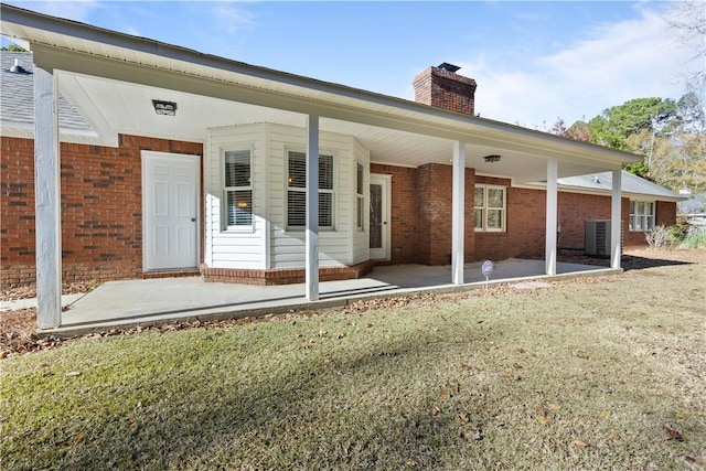 rear view of property with a lawn, central AC unit, and a patio area