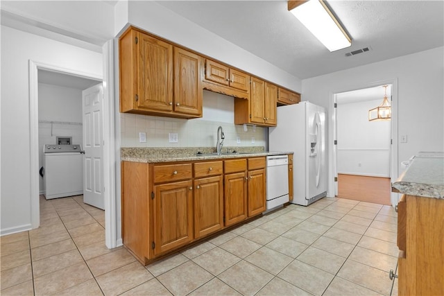 kitchen featuring sink, tasteful backsplash, white appliances, washer / dryer, and light tile patterned flooring