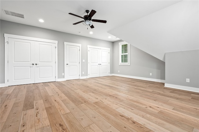 additional living space with light wood-type flooring, ceiling fan, baseboards, and visible vents