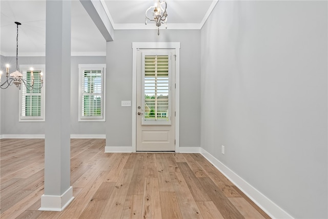 foyer entrance featuring light wood-type flooring, crown molding, and a notable chandelier