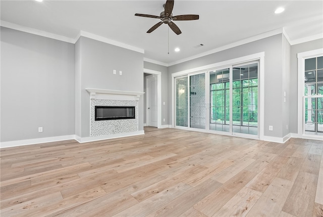 unfurnished living room featuring ceiling fan, light wood-type flooring, crown molding, recessed lighting, and a tile fireplace