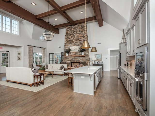 kitchen with a chandelier, a high ceiling, light countertops, open floor plan, and beam ceiling
