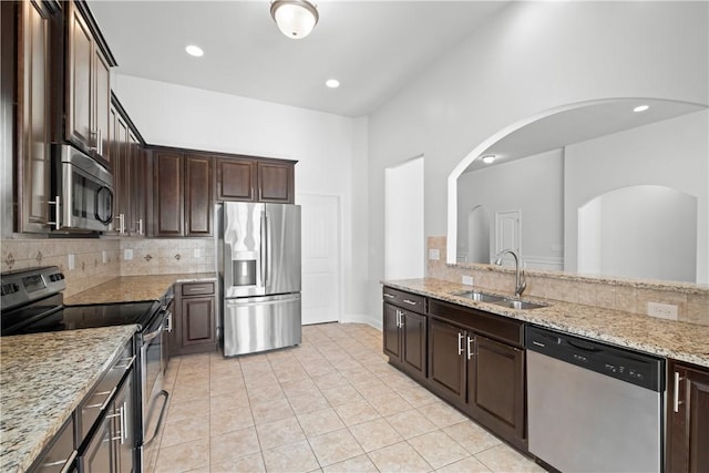 2711 Tara Ct, Opelika, AL 36804 - kitchen with appliances with stainless steel finishes, decorative backsplash, dark brown cabinetry, light tile patterned floors, and recessed lighting