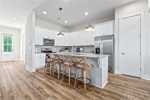617 Cameron Ct, Auburn, AL 36830 - kitchen featuring stainless steel appliances, light wood-style flooring, a sink, a kitchen breakfast bar, and a kitchen island with sink