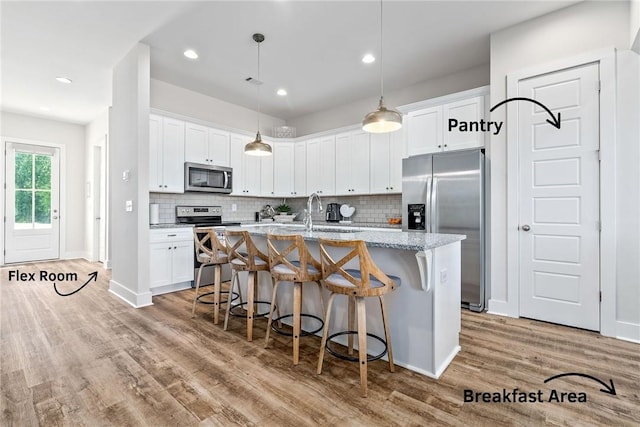 617 Cameron Ct, Auburn, AL 36830 - kitchen with appliances with stainless steel finishes, light wood-style flooring, a kitchen breakfast bar, a center island with sink, and recessed lighting