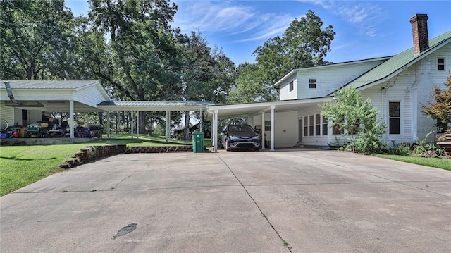 exterior space featuring an attached carport, a lawn, metal roof, and driveway