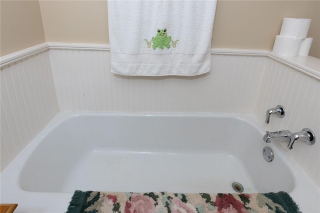 bathroom with a bath and a wainscoted wall