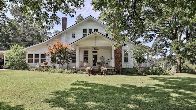 view of front facade with a chimney, a front yard, a porch, and a ceiling fan